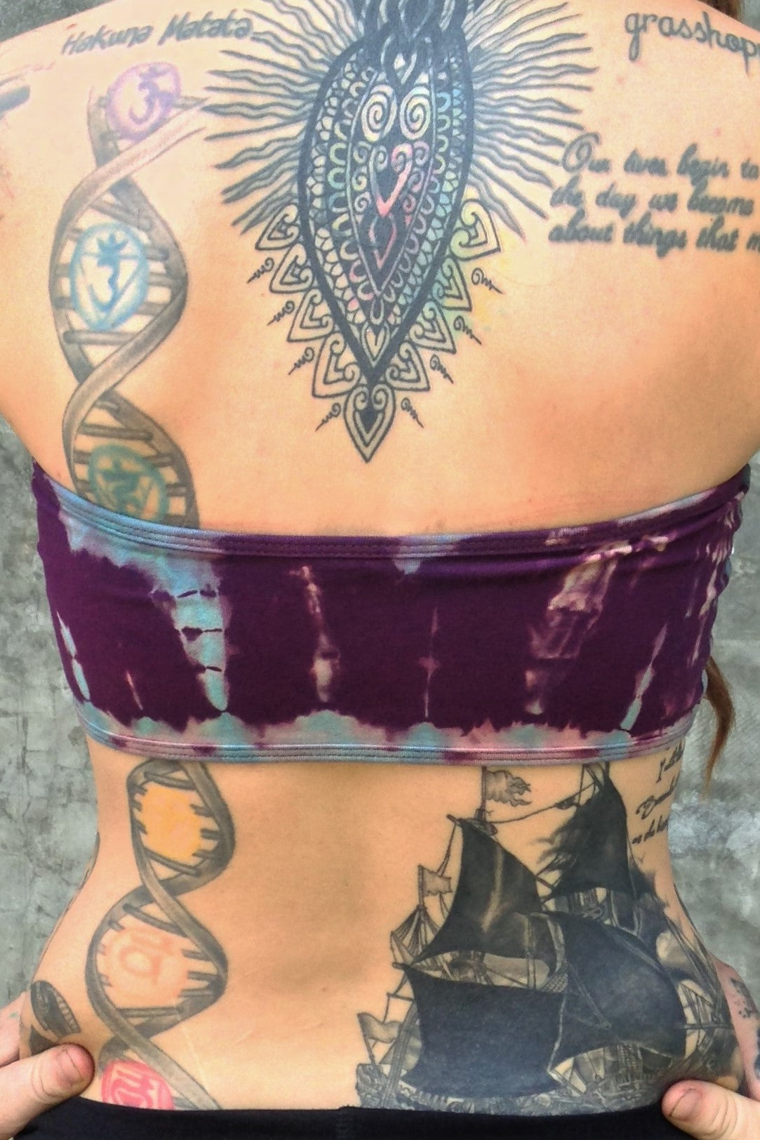 Back view of strapless view of Amethyst Tie Dye Bandeau. Purple with blue streaks and small lotus flower embroidery on back.