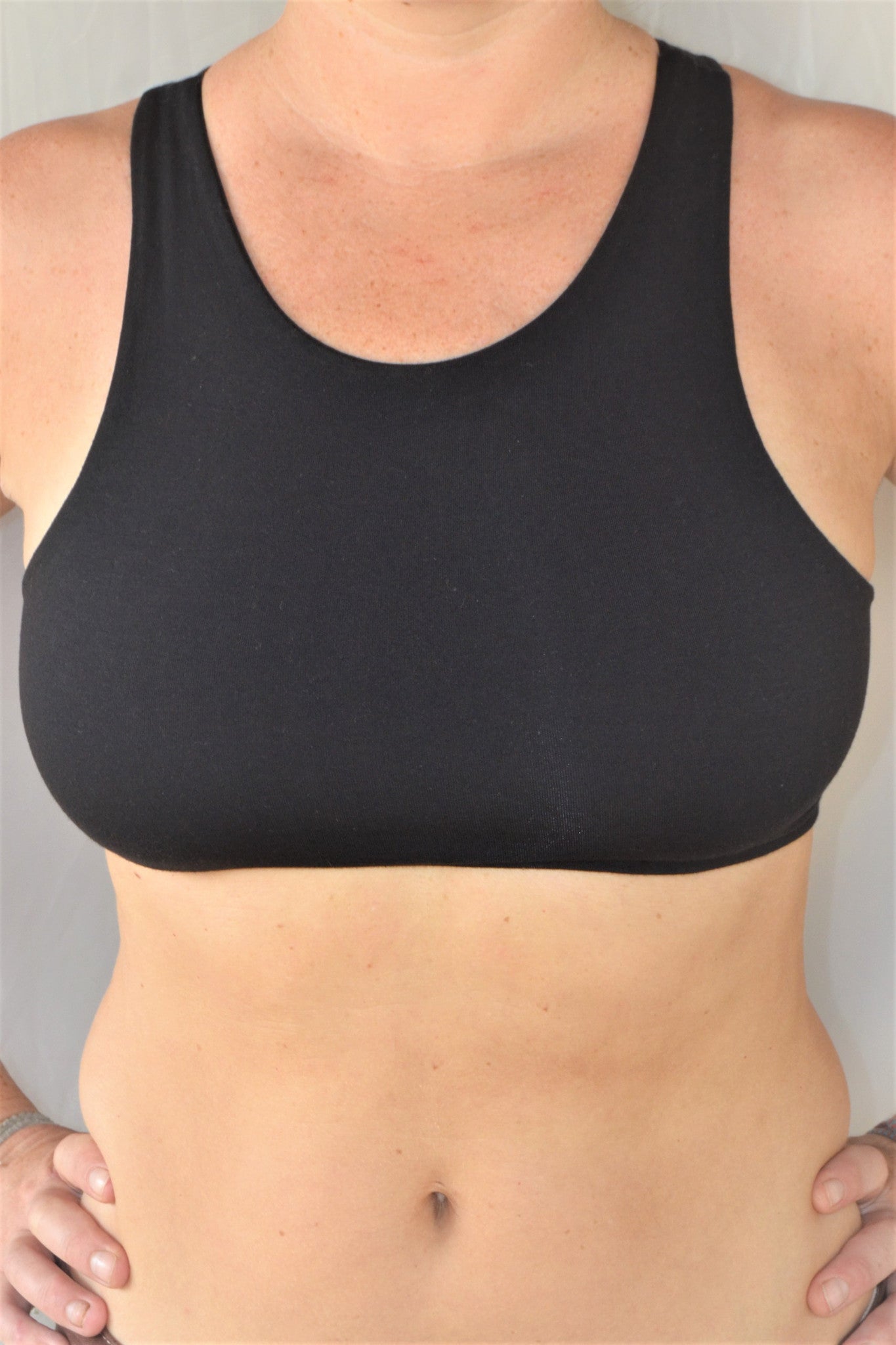 Solid black yoga crop top bra that accentuates the natural beauty of a woman's back with light support and lace up corset back, perfect for festival season.