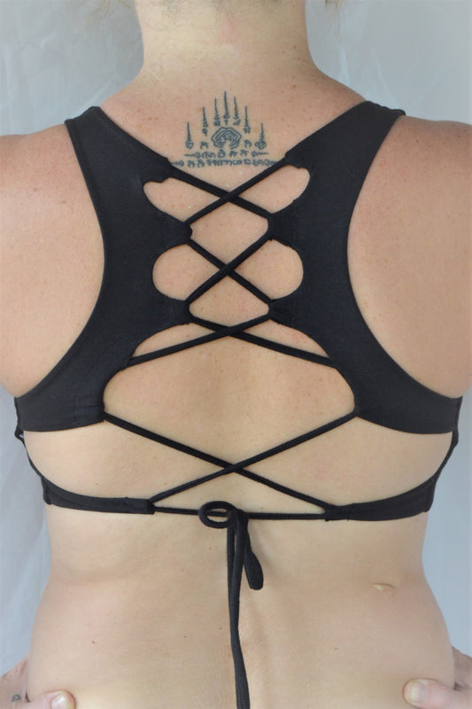 Solid black yoga crop top bra that accentuates the natural beauty of a woman's back with light support and lace up corset back, perfect for festival season.