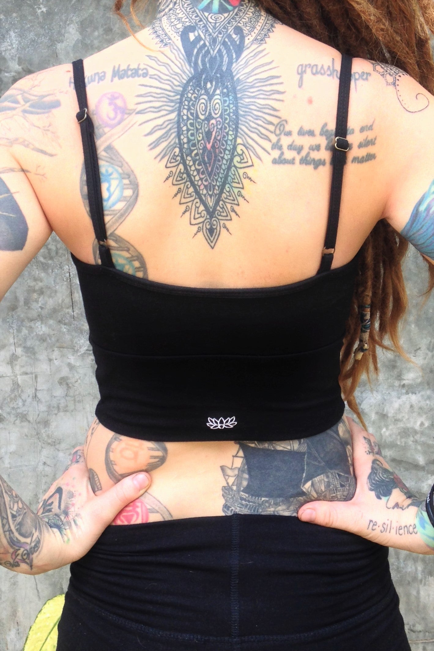 Back view of Blissed Out Crop Tank with adjustable spaghetti straps in solid Forest green with small Lotus Flower embroidery on center bottom of back.