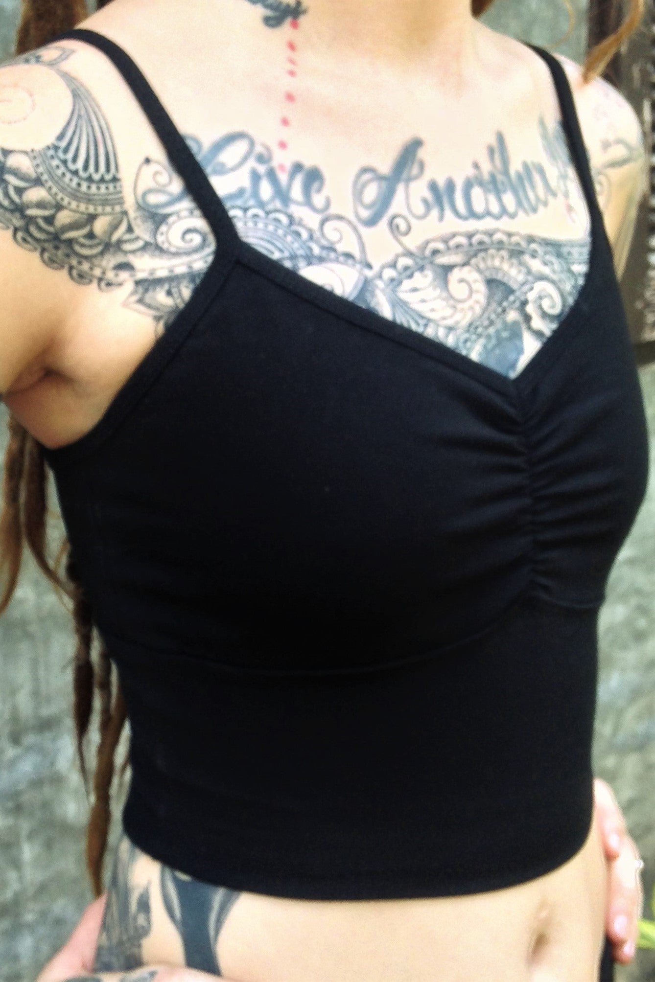 Side view of black Onyx Blissed Out Crop Tank by Lotus Tribe with adjustable spaghetti straps and scrunched center puckering between the breasts. Made from 90% Organic Cotton with 10% Spandex.