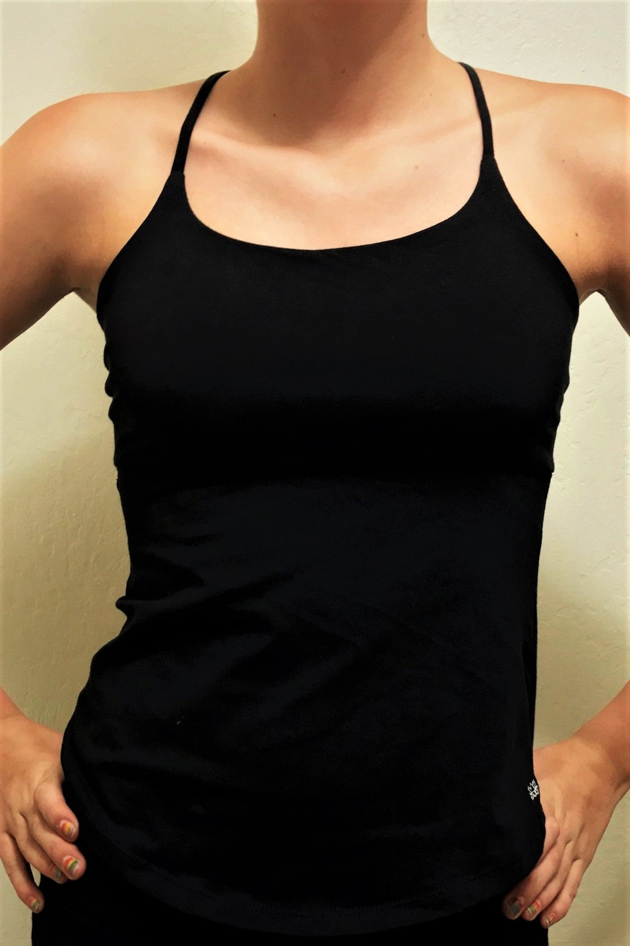 Front view of solid black Tie Back Tank has spaghetti straps, underbust seam and rounded bottom edge. Made of stretchy 90% cotton with 10% spandex.