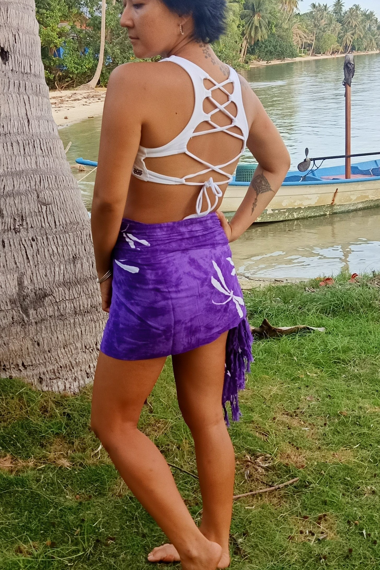 Purple sarong with white dragonfly pattern worn as wrap around mink skirt. Shown with white goddess top on woman at the beach.