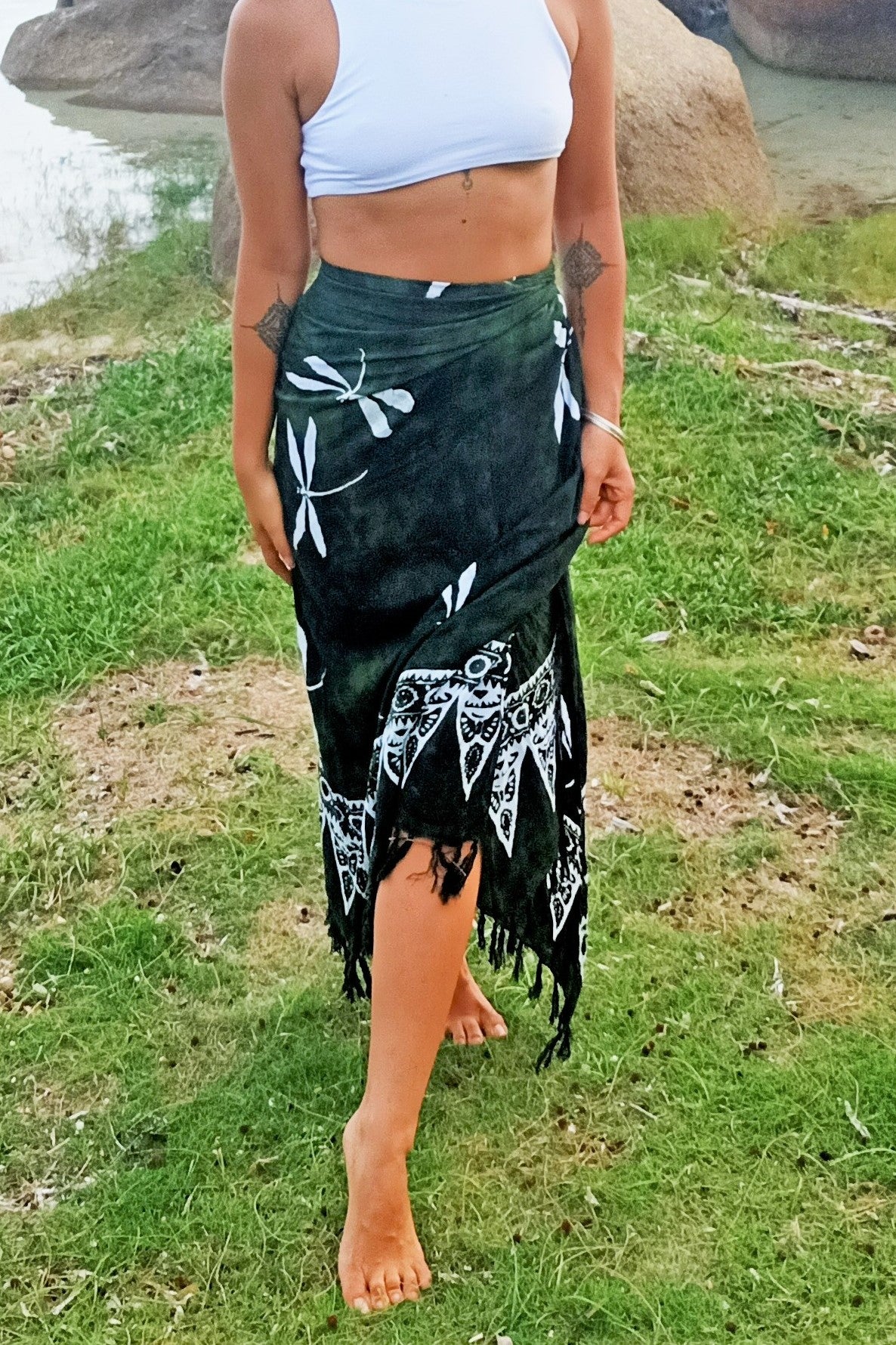 Sarong worn as wrap around beach cover up skirt. Green background with white dragonfly pattern.