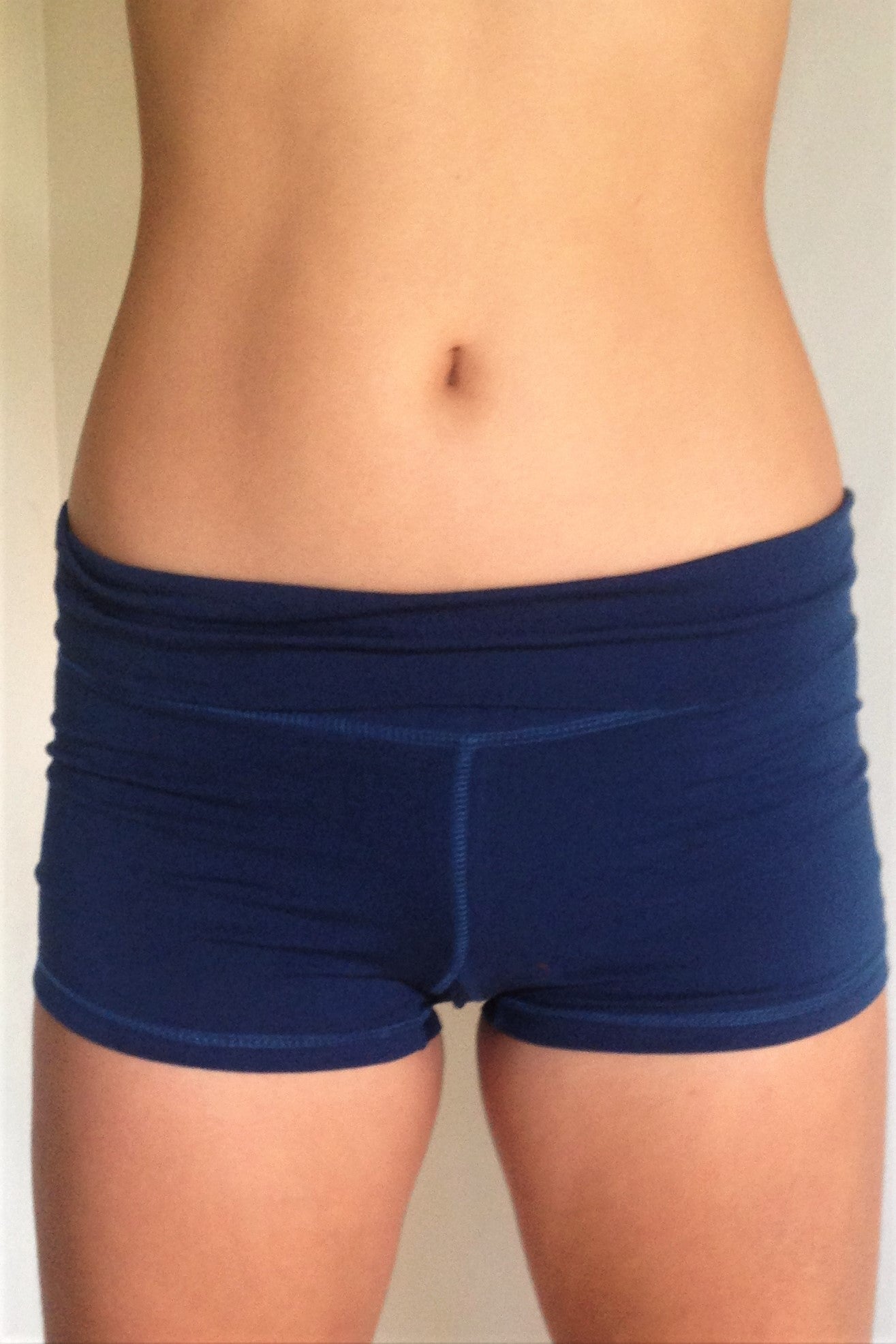 Front view of solid Cobalt blue yoga shorts with fold over waist, can be worn higher waisted, or low on the hips. Small black Lotus Flower embroidery. 90% cotton 10% spandex.