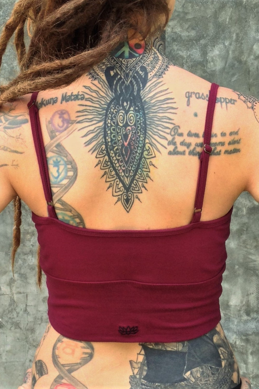 Back of organic cotton crop tank with adjustable spaghetti straps and scrunched center puckering between the breasts in solid Garnet color with small black Lotus Flower embroidery.