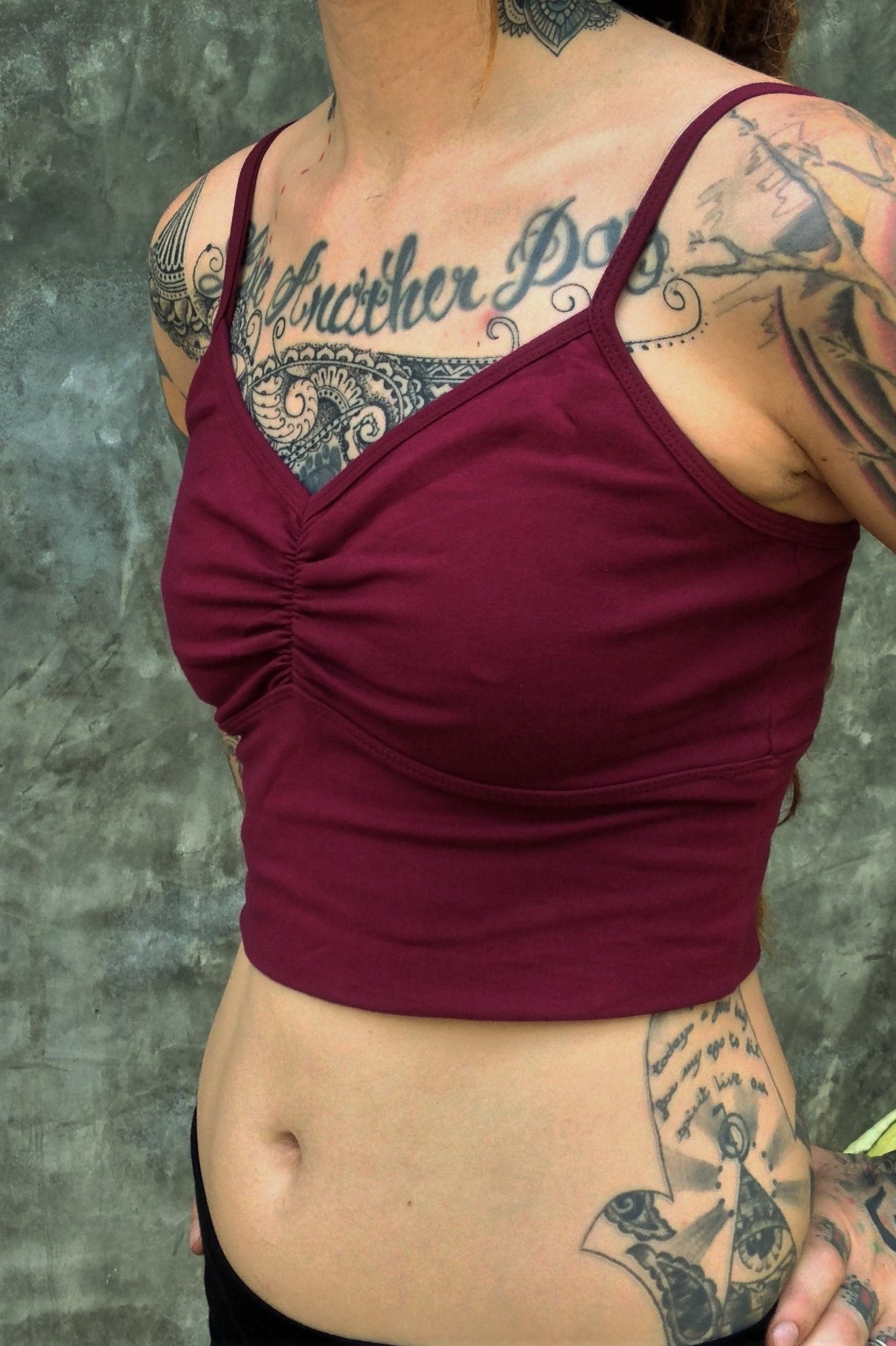 Side view of organic cotton crop tank with adjustable spaghetti straps and scrunched center puckering between the breasts in solid Garnet color. 