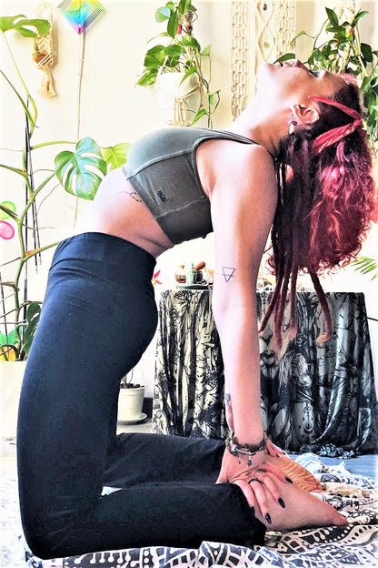 Onyx Flared  bottom yoga pants shown on woman in camel yoga pose with Sage Sunburst Sports Bra by Lotus Tribe Clothing. 