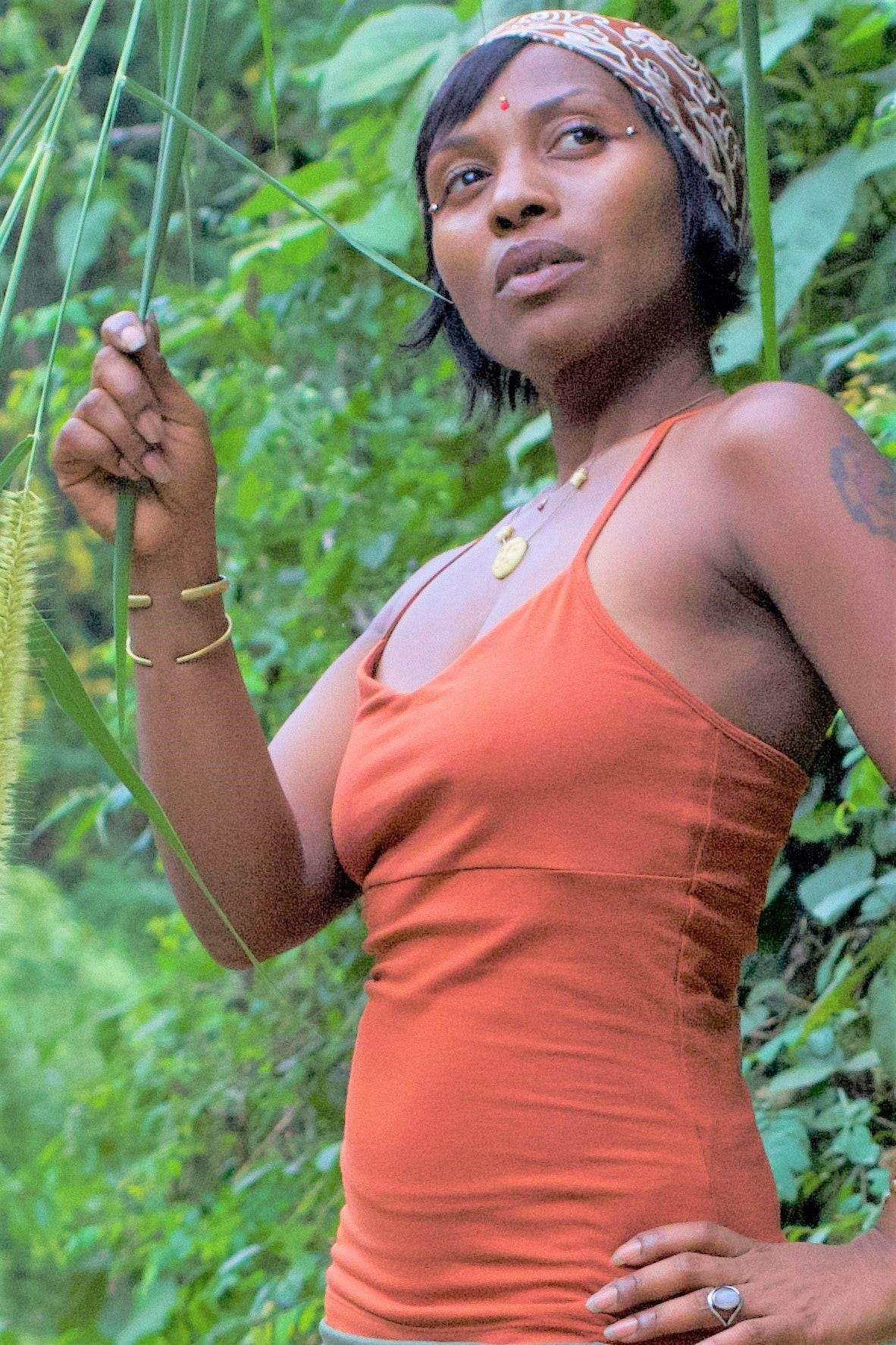 Woman in contemplation wearing Rust Ananda Tank in nature. 