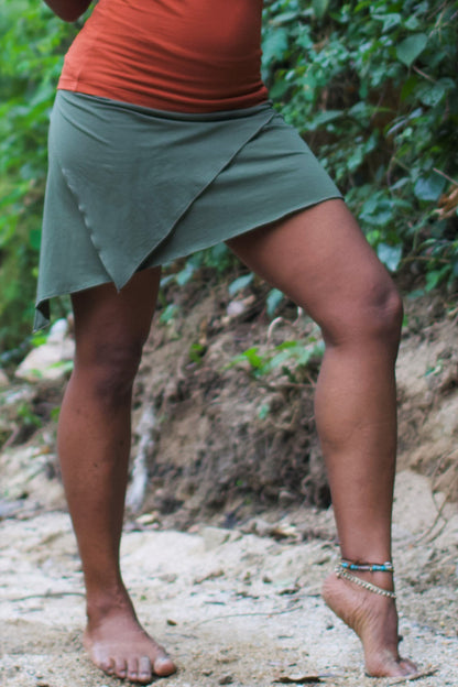 Sage green mini skirt with triangular front layer shown. Stretchy nomad skirt worn over bare legs.