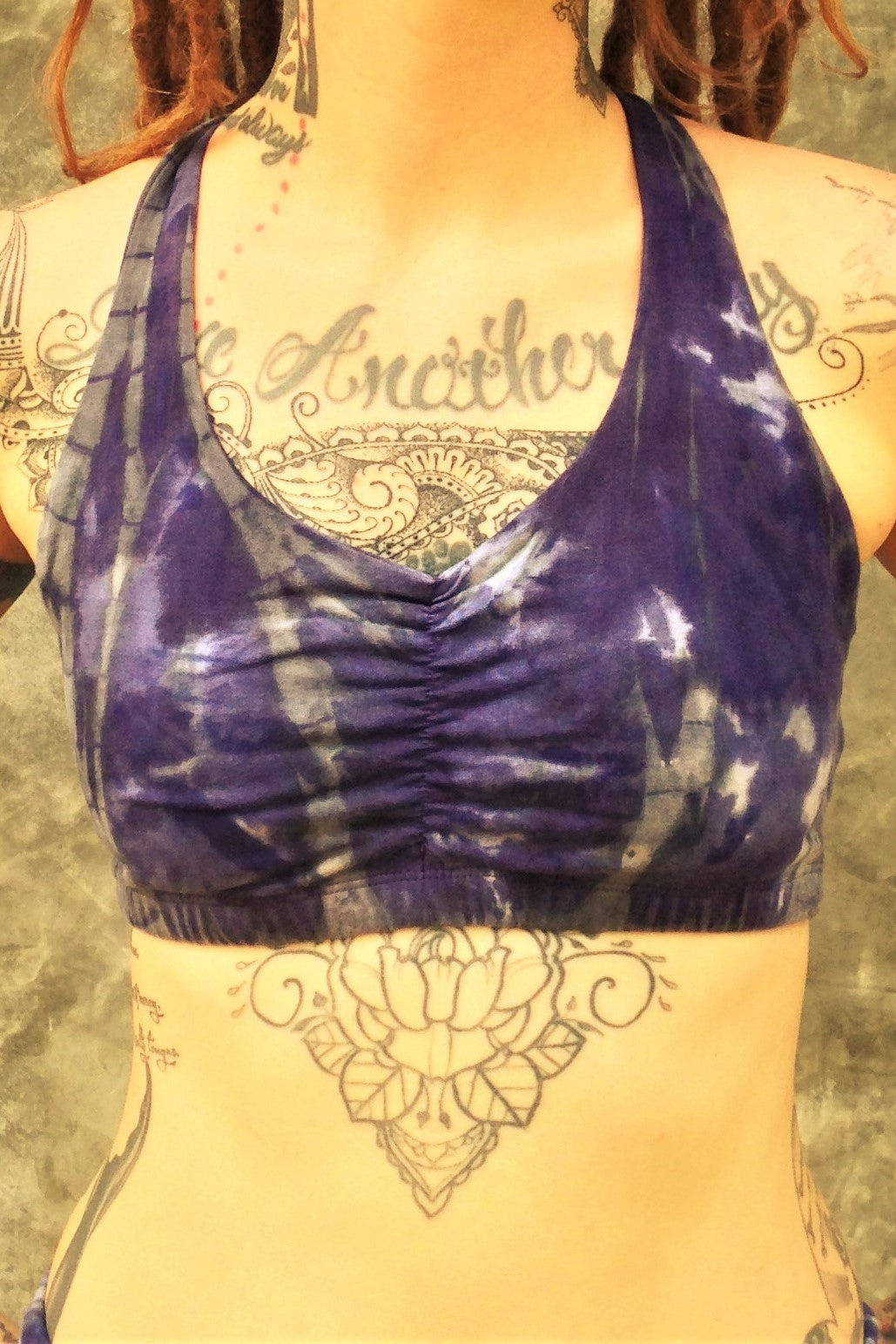 Front view of shakti Sportsbra in Wildflower tie dye is a full coverage bra with scrunching between the breasts in cool purple hues with grey streaks and white highlights. 