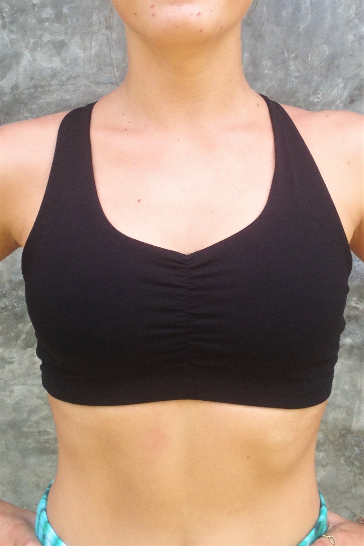 Front view of black Onyx Sportsbra with scrunching between breast and wide shoulder straps. 