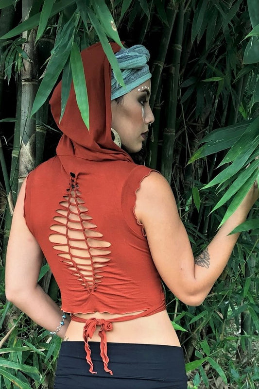 Sleeveless Rust Ninja Wraps come with oversized hood and see thru detail on back worn by woman in bamboo forest with tribal face paint. . Soft and silky, perfect for layering.